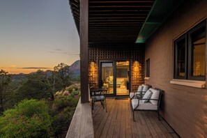 Um deck de madeira com área de estar externa e porta de vidro que dá para um cômodo.