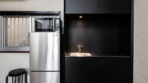 A compact kitchen with a stainless steel refrigerator, a microwave, and a sink. - Volcano (Kagoshima)