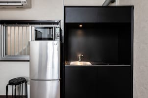 Cocina compacta con refrigerador de acero inoxidable, microondas y pileta.