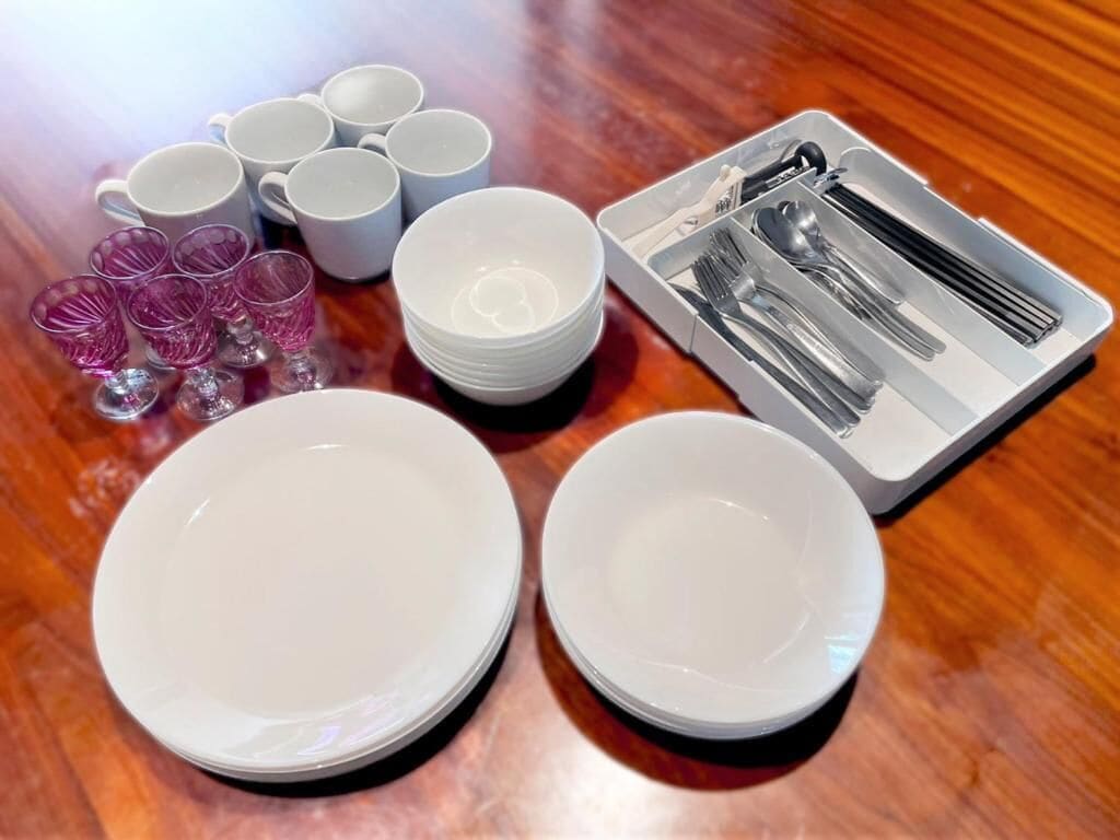 A table set with white plates, bowls, cups, and cutlery.