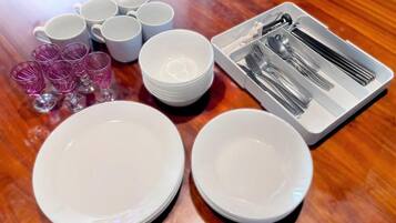 Una mesa servida con platos, tazones, vasos y cubiertos blancos.