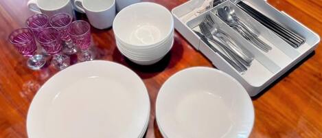 A table set with white plates, bowls, cups, and cutlery.