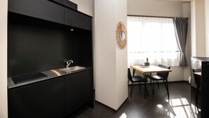 A compact kitchen with a black countertop, a sink, and a dining area with a table and chairs. - Volcano (Kagoshima)