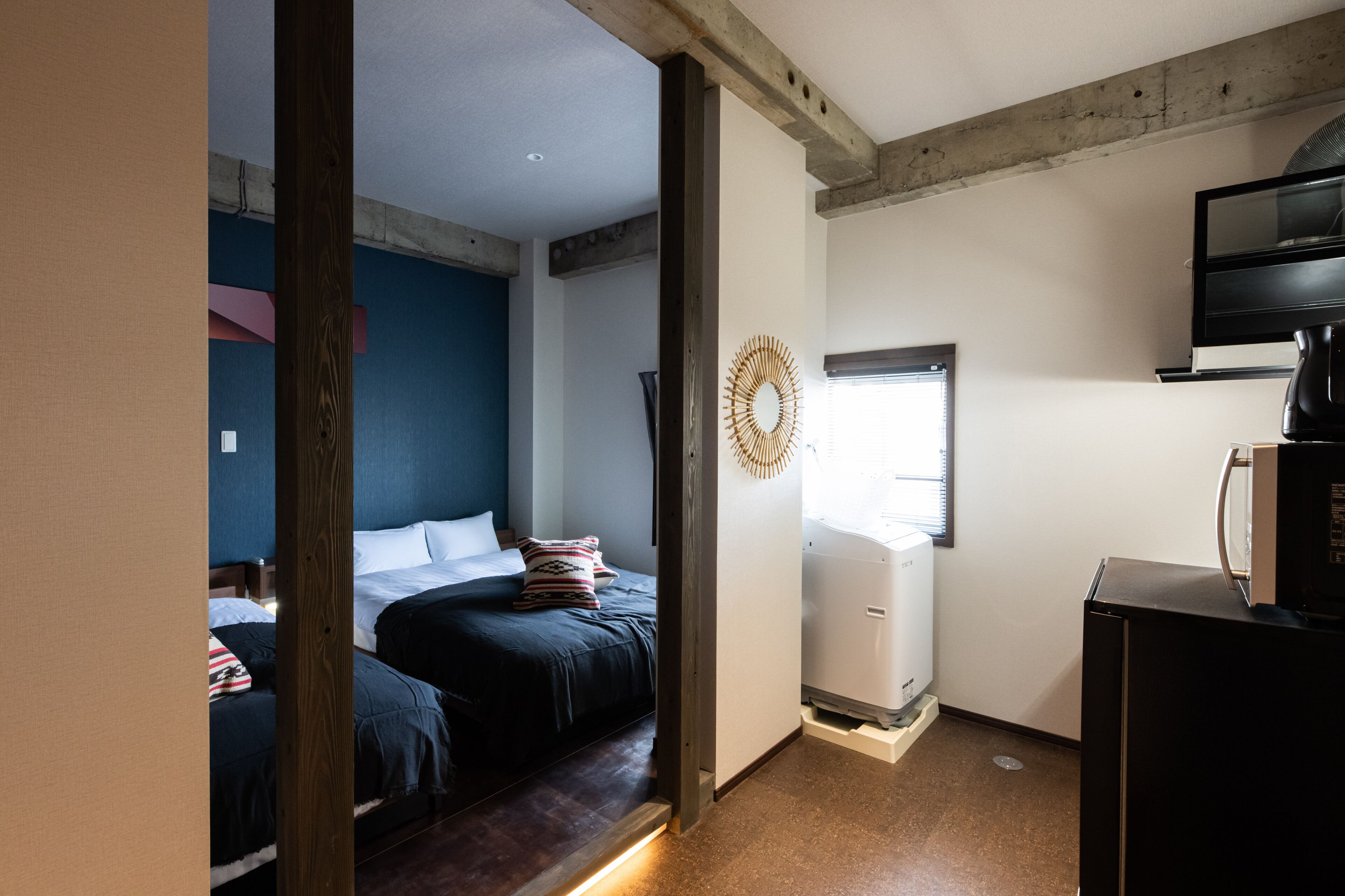 Quarto com duas camas, TV e uma kitchenette pequena.