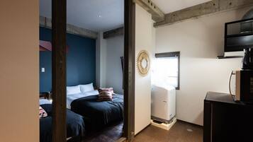 Quarto com duas camas, TV e uma kitchenette pequena.