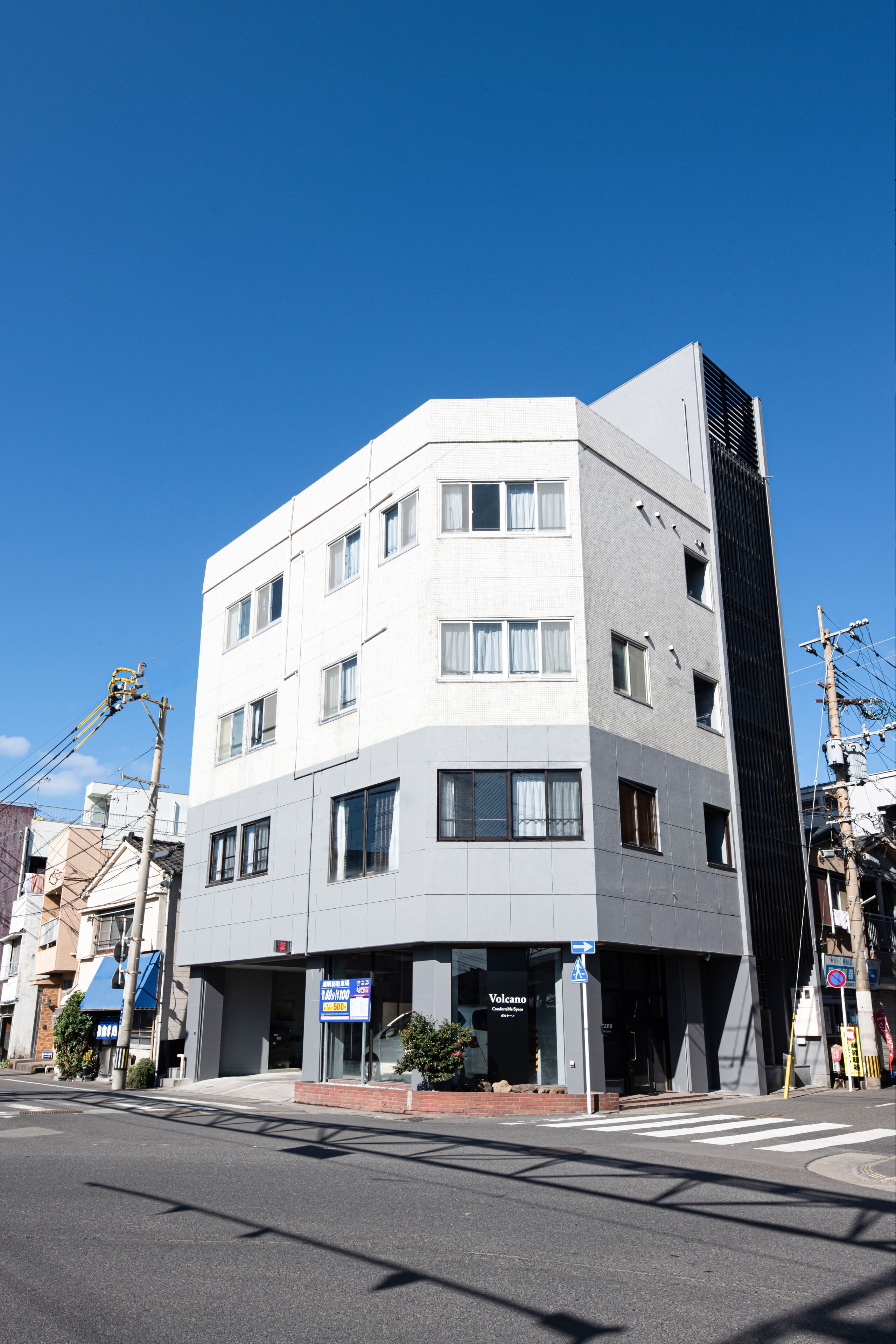 Un edificio de varios pisos con fachada plana, varias ventanas y una entrada visible.