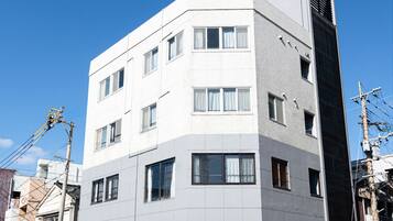 Un edificio de varios pisos con fachada plana, varias ventanas y una entrada visible.