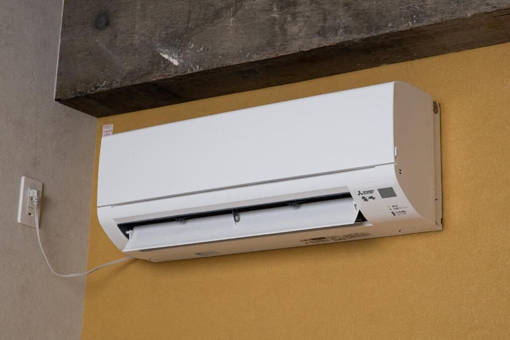 Un equipo de aire acondicionado blanco instalado en una pared, con un enchufe visible.
