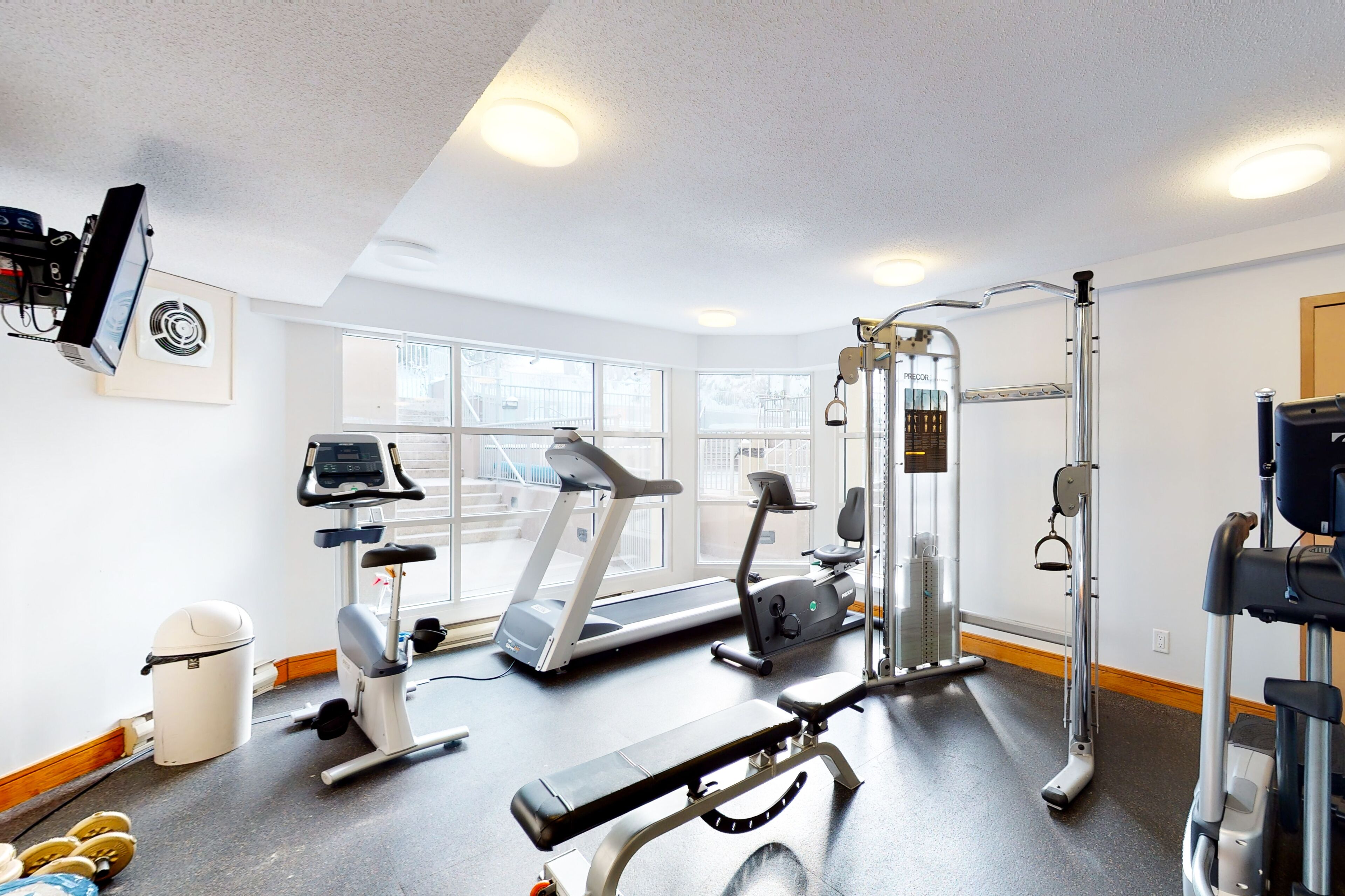 Een fitnessruimte met loopbanden, elliptische trainers en gewichten.