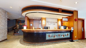 Ein Empfangsbereich mit einer gebogenen Theke, einem Schild für Woodrun Lodge und einer Treppe im Hintergrund.