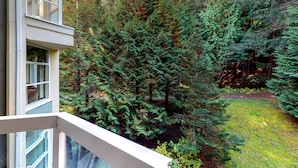 Ein Wohngebäude mit Balkon und Blick auf einen dichten Wald.