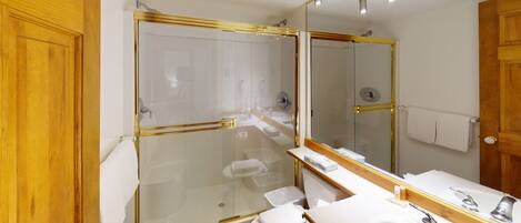 A modern bathroom with a glass-enclosed shower, a white sink, and a large mirror.