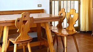 Een houten eettafel met stoelen, een bank en een raam met gordijnen.