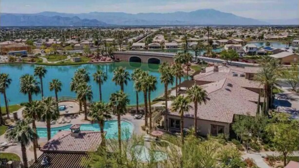 A resort with multiple swimming pools, palm trees, and a bridge connecting different areas.