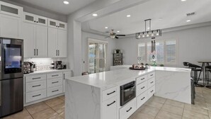 A modern kitchen with white cabinetry, a large island, and a built-in oven.