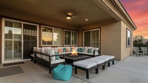A covered patio with a fire pit, seating area, and large windows.