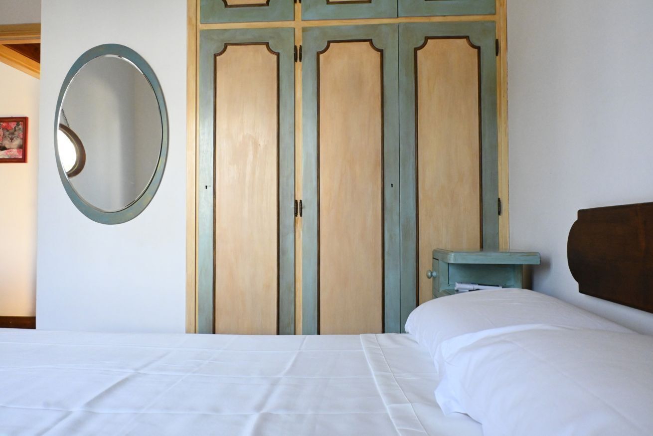 A bedroom with a bed, a wardrobe, and a small table.