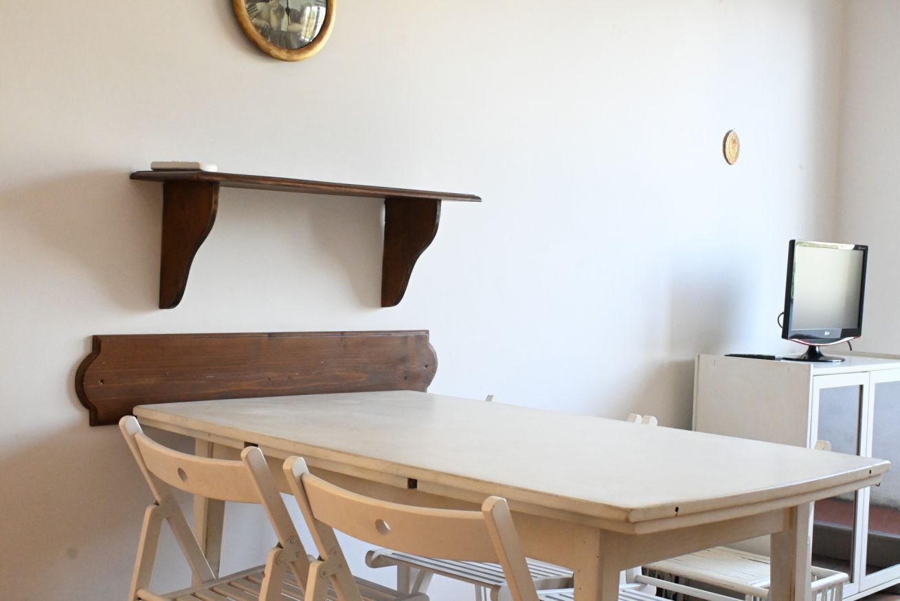 Un espace repas comprenant une table, des chaises, un téléviseur et une étagère.