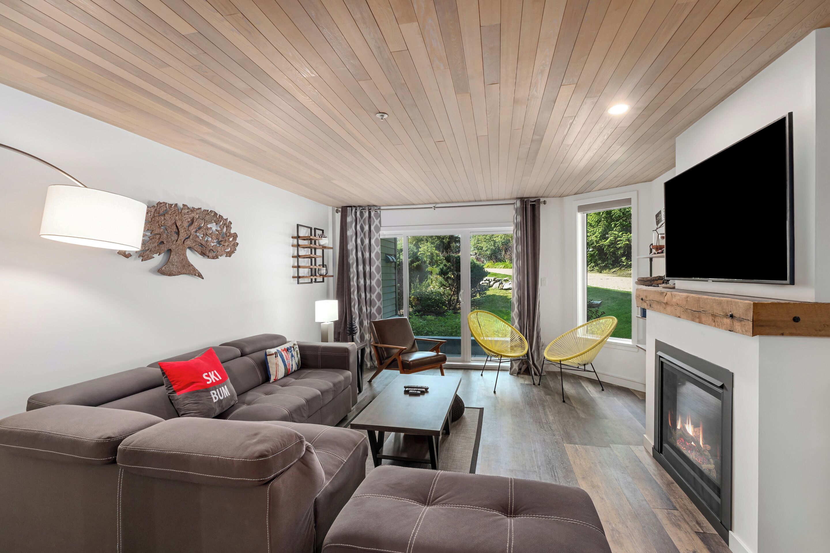 Un salon moderne avec un canapé, des fauteuils, une cheminée et un téléviseur.