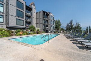 Un edificio moderno con piscina y sillones de descanso.