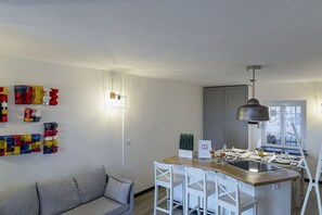 A modern kitchen with a central island, white bar stools, and a pendant light. - Sapore di Sale by Wonderful Italy (Genova)
