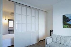 Une pièce dotée d’une porte coulissante donnant accès à une salle de bain, avec un lit et un tableau accroché au mur.