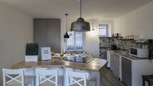 Eine moderne Küche mit Kochinsel, weißen Stühlen, einer Pendelleuchte und einer gefliesten Spritzschutzwand.
