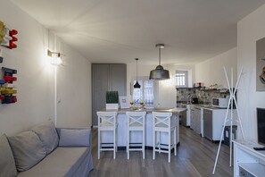Une cuisine moderne avec des meubles blancs, un coin repas avec des chaises blanches et un canapé.