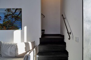 A staircase with a metal handrail, a painting on the wall, and a sofa with a cushion. - Sapore di Sale by Wonderful Italy (Genova)