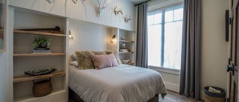 A bedroom with a bed, shelves, and wall-mounted deer antlers.