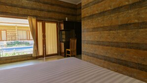 A room with a bed, a chair, a TV, and a view of the outside. - Manik Homestay Uluwatu by Zuzu (Pecatu)