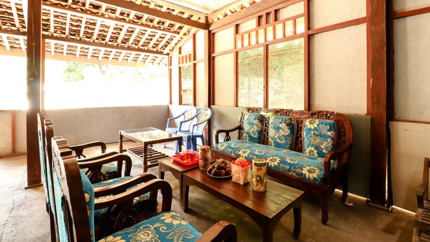 A traditional-style room with a wooden ceiling, a sofa with floral upholstery, and a dining table with chairs.