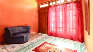 A room with a dark-colored sofa, a patterned rug, and a window with red curtains.