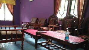 A room with a long wooden table, several chairs, and a window with curtains. - Sutrisno Homestay - Hostel (Kokap)