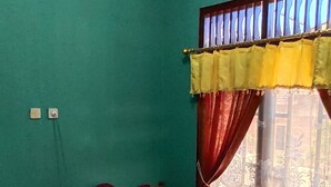 A room with a bed, a window with curtains, a desk, and a chair. - Sutrisno Homestay - Hostel (Kokap)