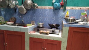 A kitchen with a stove, pots, and a cutting board. - Sutrisno Homestay - Hostel (Kokap)