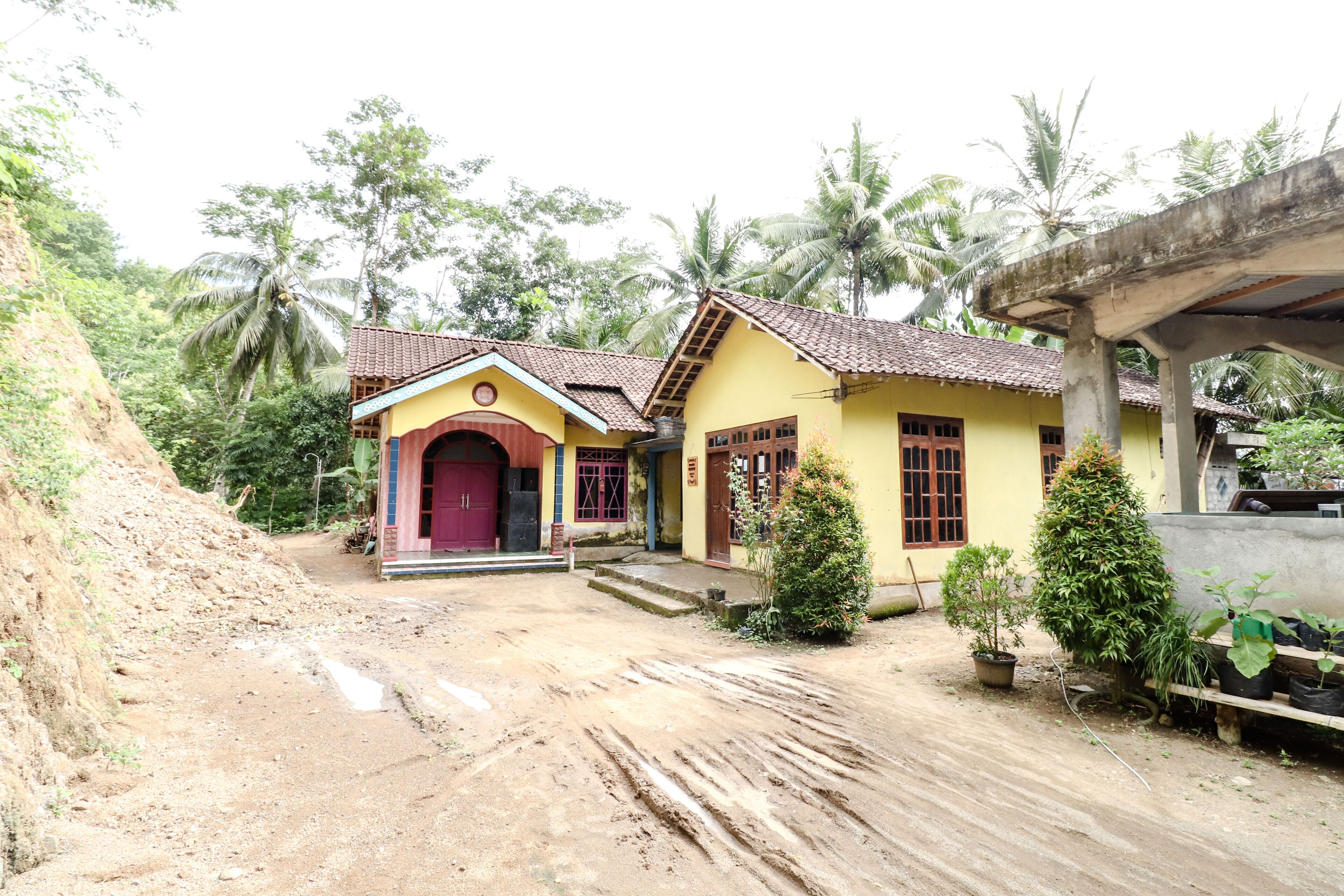 A two-story yellow building with a red door and a small porch.