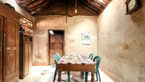 Uma sala de jantar com uma mesa de madeira, cadeiras azuis, um espanador e um relógio na parede.