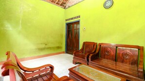 Quarto com parede verde, móveis de madeira, piso de azulejos e porta com design decorativo.