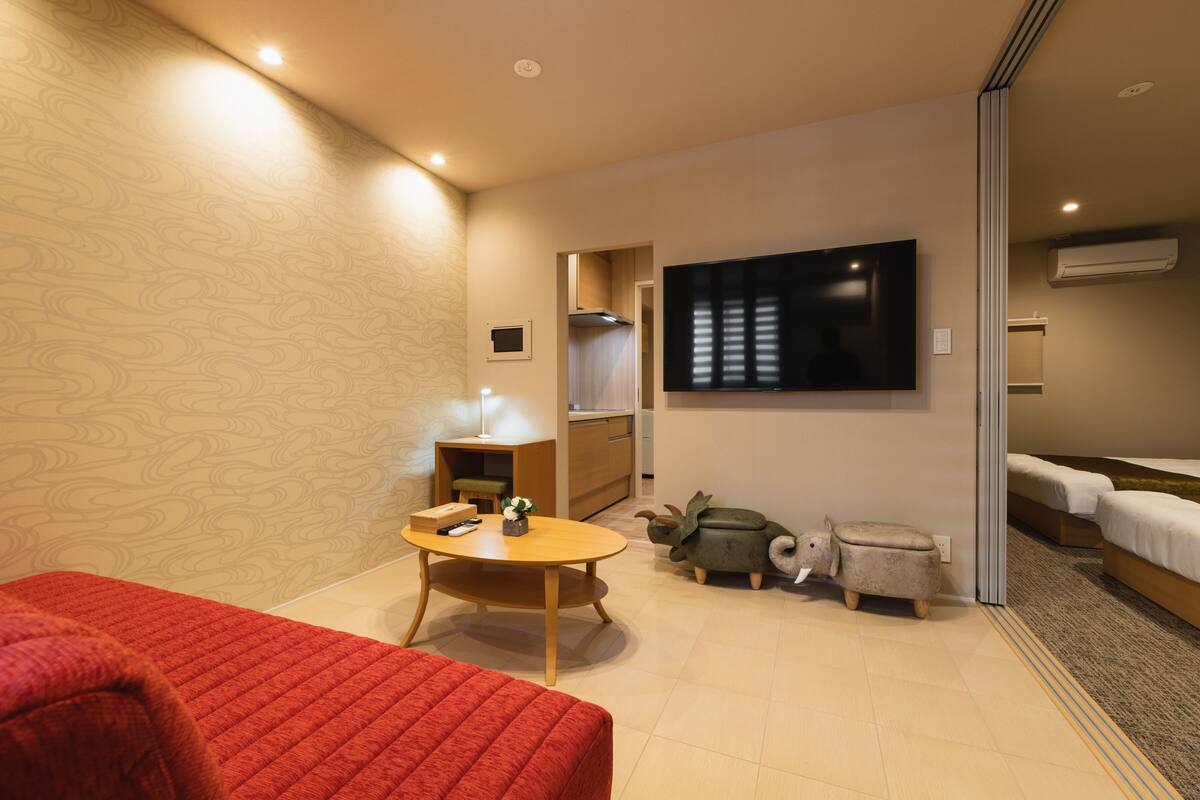 A hotel room with a bed, a desk, a chair, a television, and a small dinosaur toy.