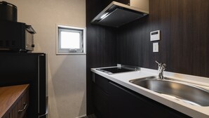 A modern kitchen with a stainless steel sink, a window, and dark wooden cabinets. - GRAND BASE Crane (Fukuoka)
