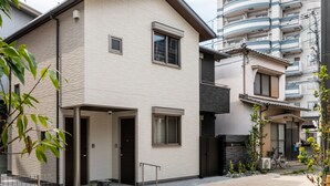 A modern residential building with a flat roof, a balcony, and a small garden area. - GRAND BASE Crane (Fukuoka)