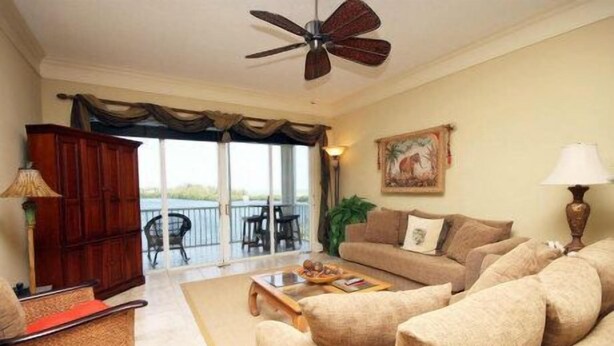 Una sala de estar con sofá, una mesa de centro y vistas a un balcón con mobiliario exterior.