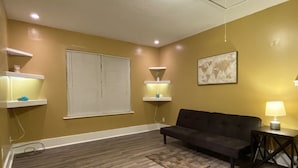 A living room with a dark sofa, a small rug, and two wall-mounted shelves with decorative items. - Special offer!!!!!!! (Dothan)