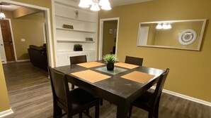 A dining area with a wooden table and chairs, a potted plant, and a wall-mounted clock. - Special offer!!!!!!! (Dothan)