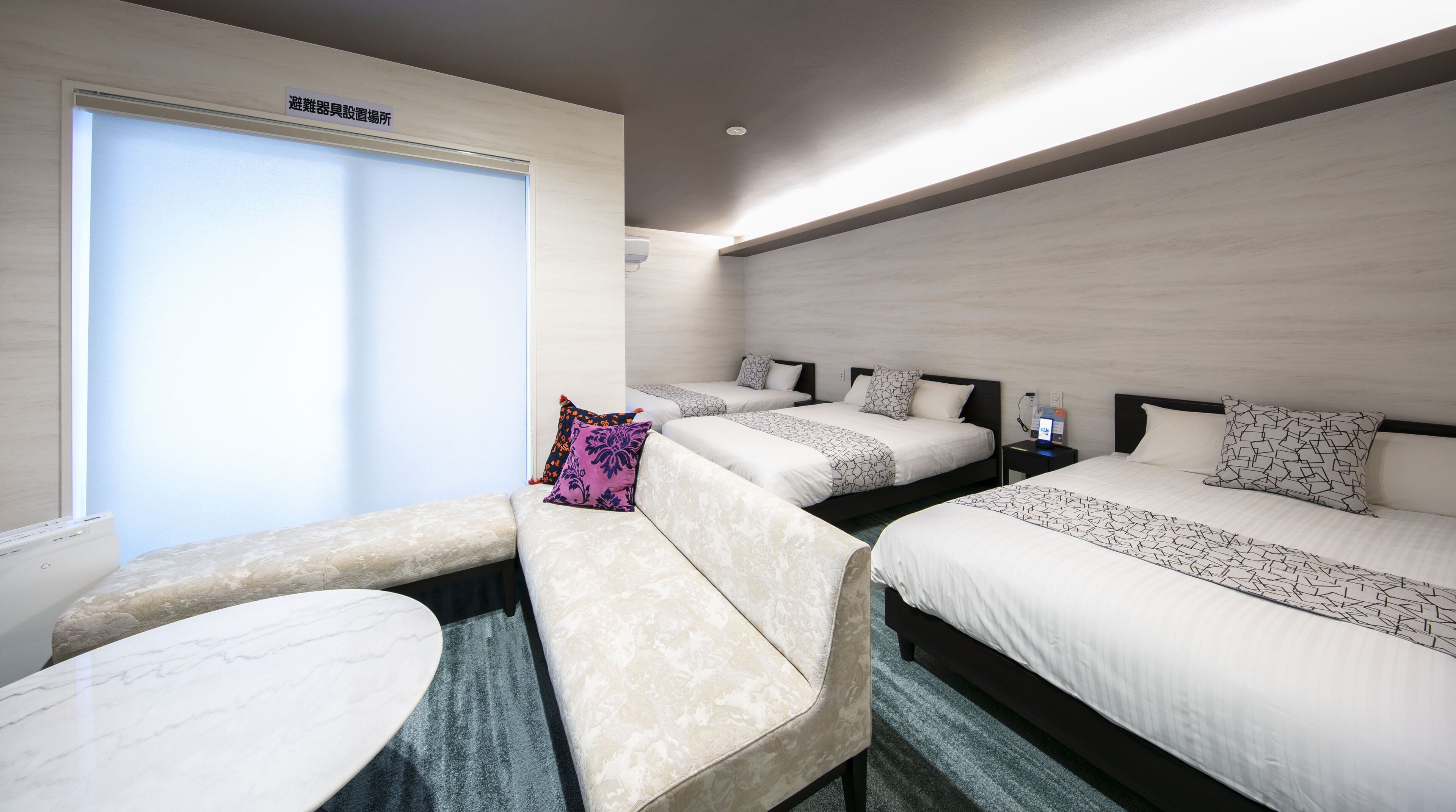 Une chambre d’hôtel avec trois lits, un canapé et une petite table.