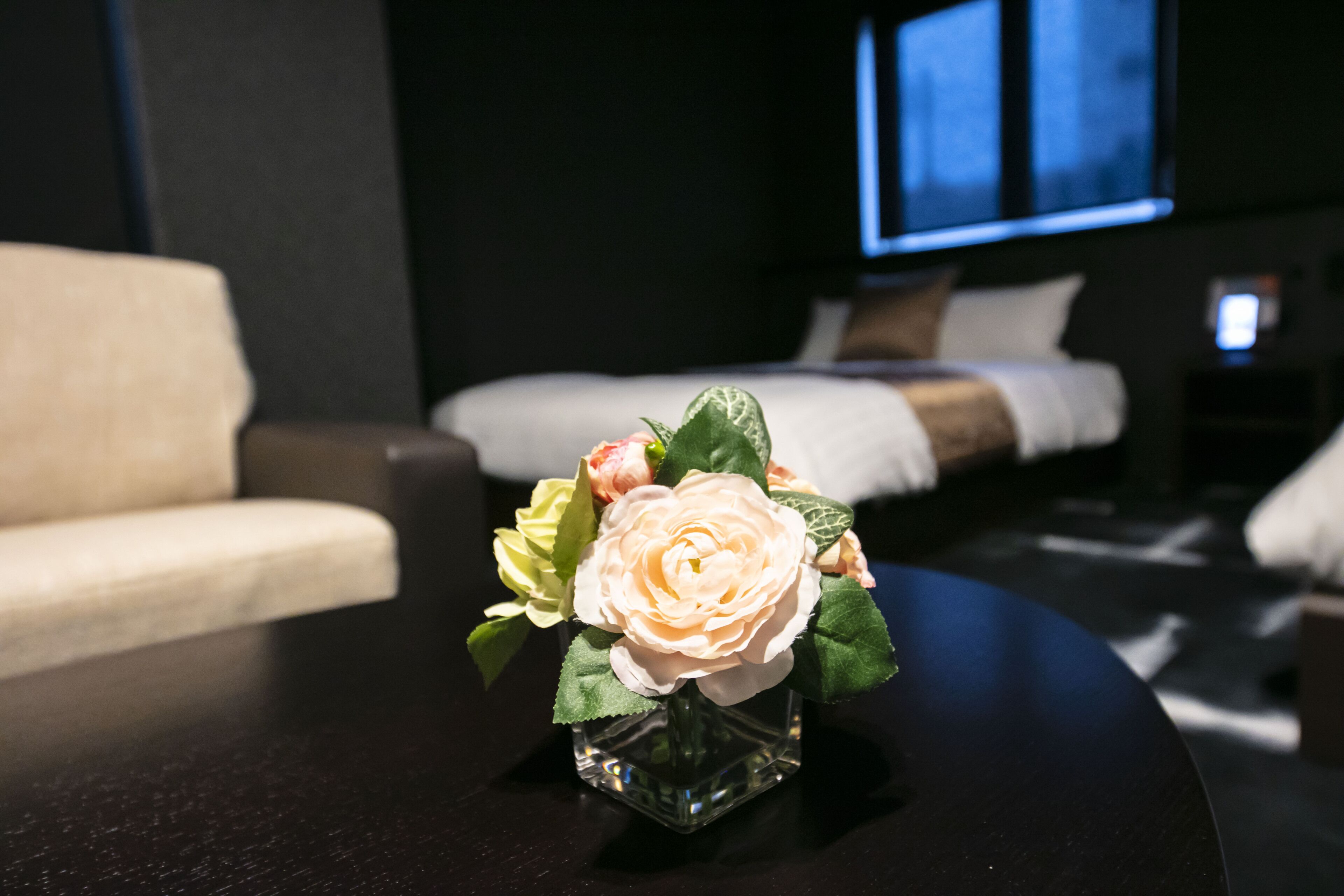 Una habitación de hotel con una cama, un sofá y una pequeña mesa con un jarrón de flores.