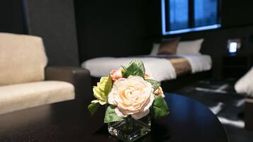 Una habitación de hotel con una cama, un sofá y una pequeña mesa con un jarrón de flores.