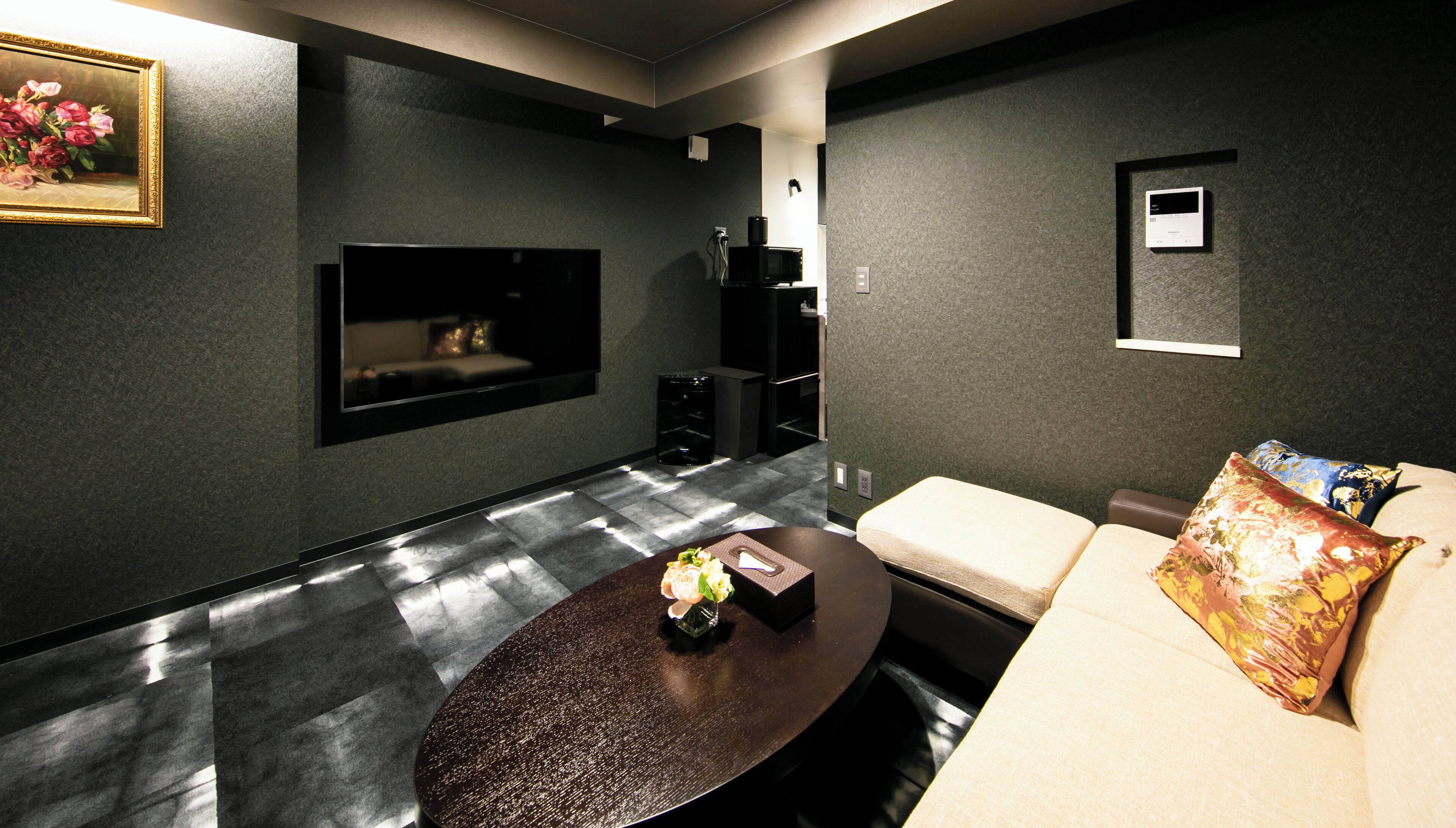 Un salon moderne avec un téléviseur à écran plat, une table basse et un canapé agrémenté de coussins décoratifs.