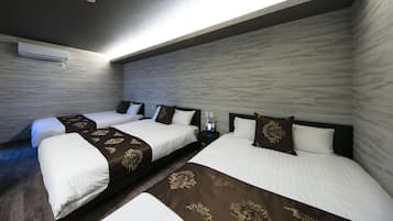 A hotel room with two beds, a nightstand with a phone and a card reader, and an air conditioning unit on the wall.